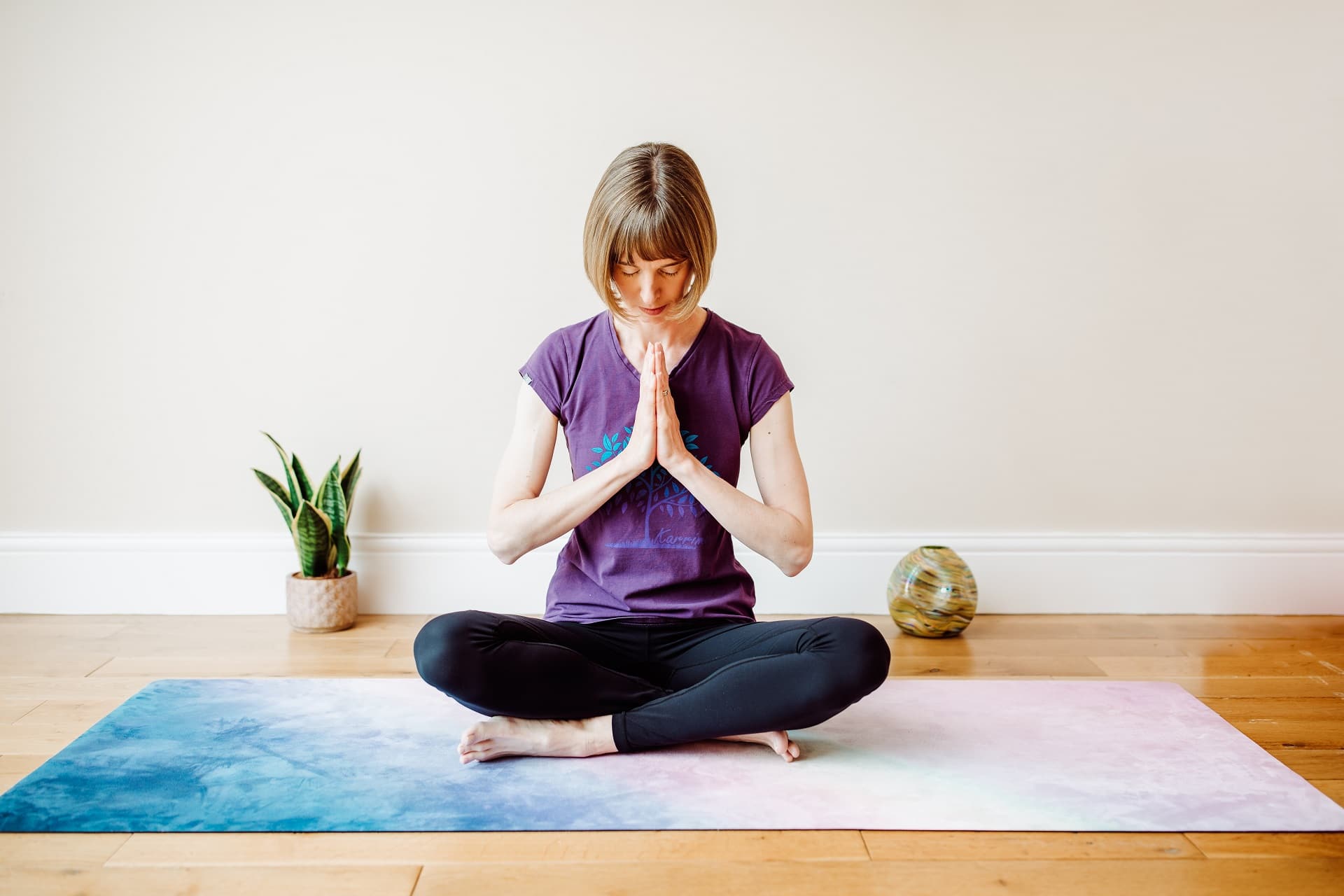 yogini in hands to heart centre pose seated on yog mat